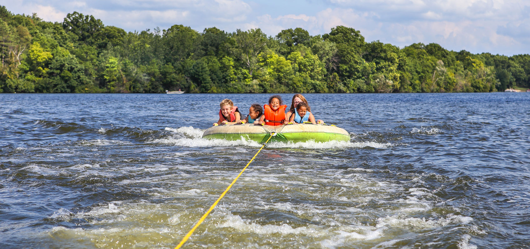 frontside view of children and adult woman on raft being pulled by a line in the water