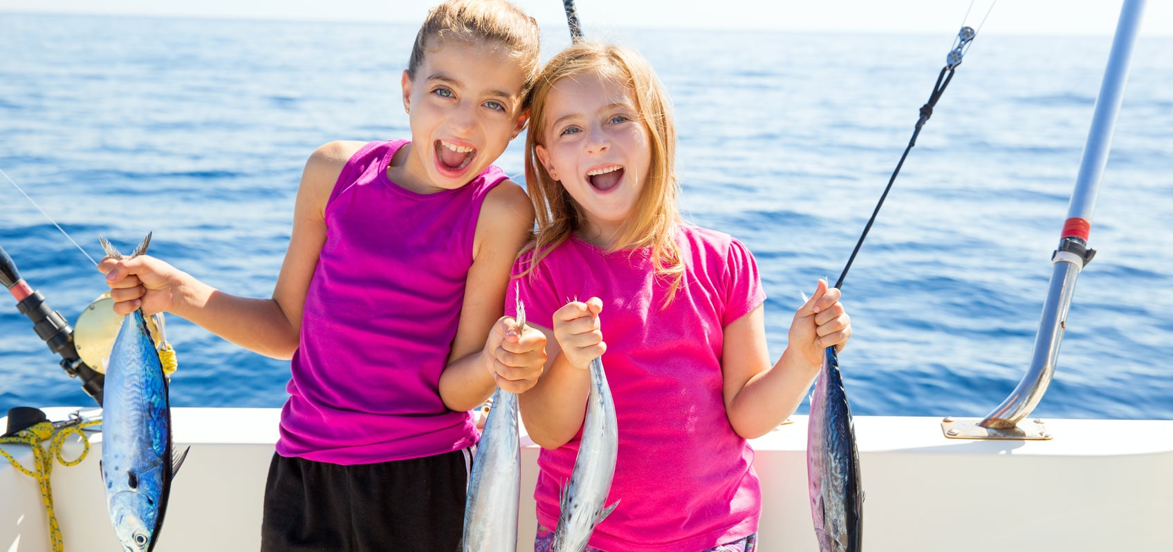 two excited little girls on a boat holding one fish in each hand