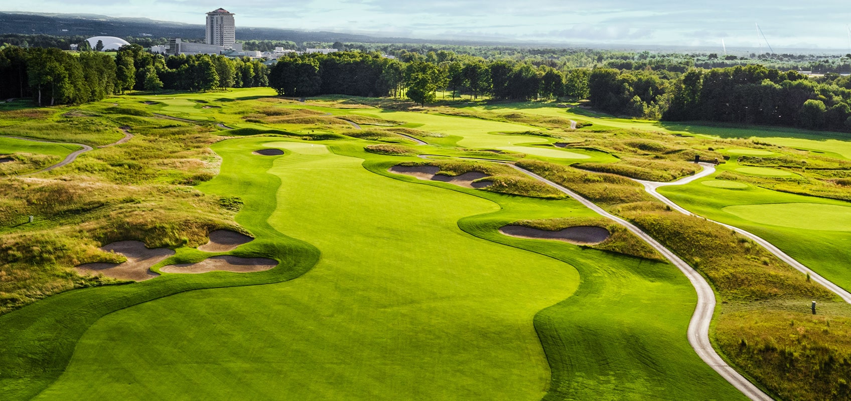 aerial view of a golf course. The golf course is green, with brown patches of sand and small ponds