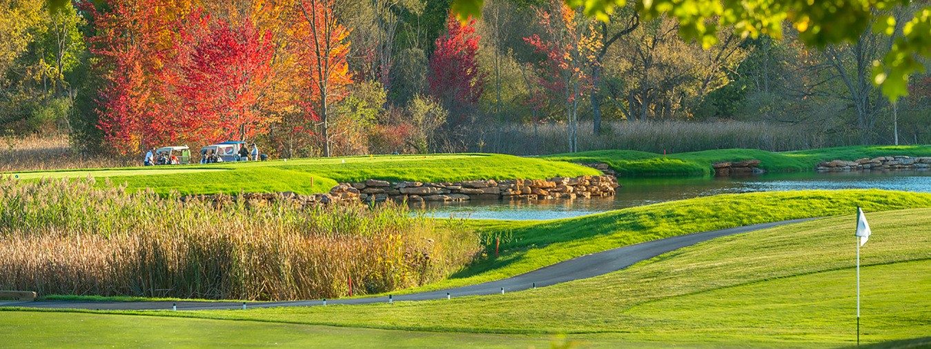 a golf course in the fall, with the colorful leaves contrasting with the green fairway