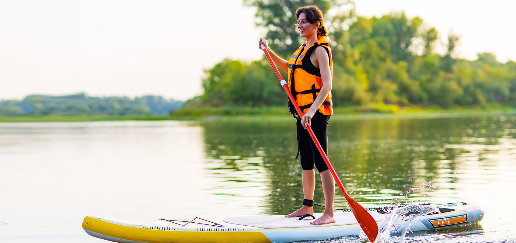 woman smiles paddling board on lake