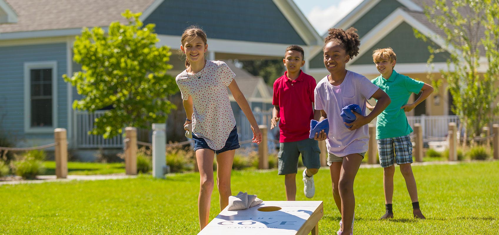 Four children playing cornhole