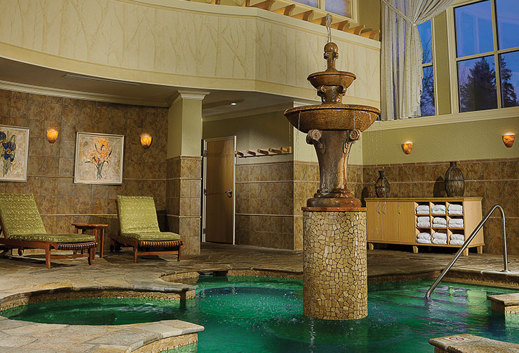 a water fountain in the middle of a swimming pool. The fountain is a multi-tiered structure, with water cascading down from each tier into the pool