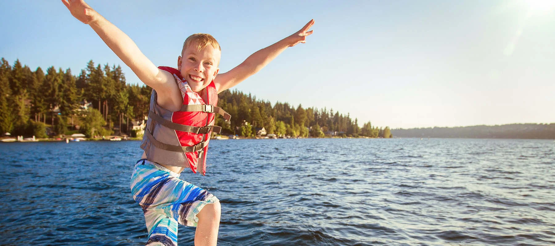 Child jumping off a boat into a lake