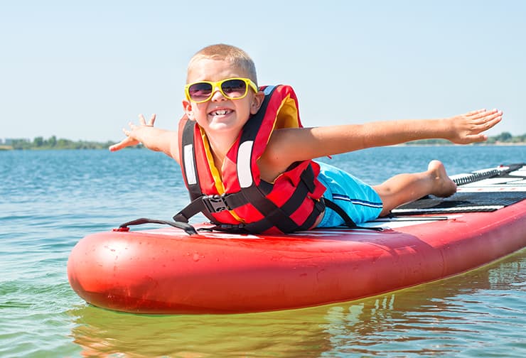 little kid smiles laying belly down on paddle board