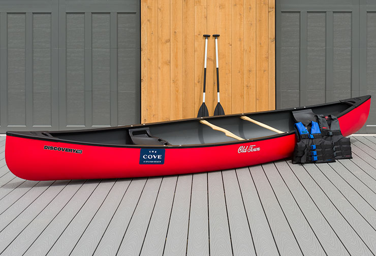 Red canoe with two paddles and two life jackets on a deck