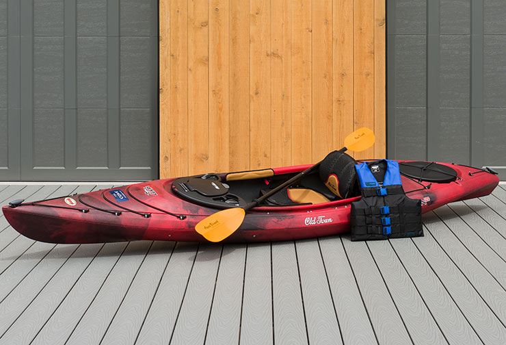 Dark Red colored kayak with a paddle  and a life jacket on a deck