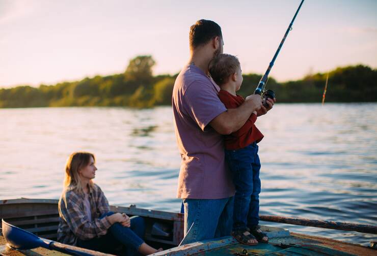 father fishing with little son and mother watching