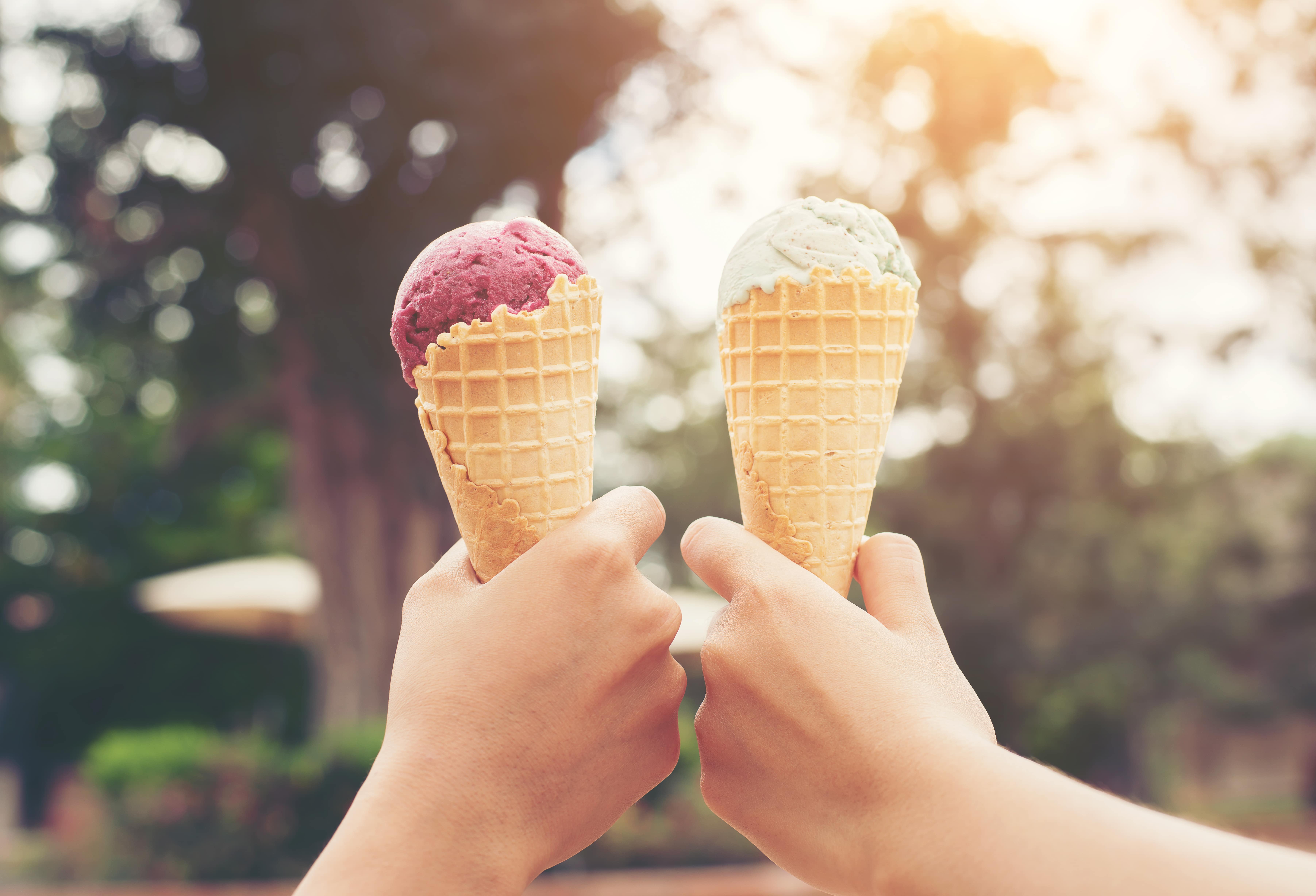 two hands holding ice cream cones