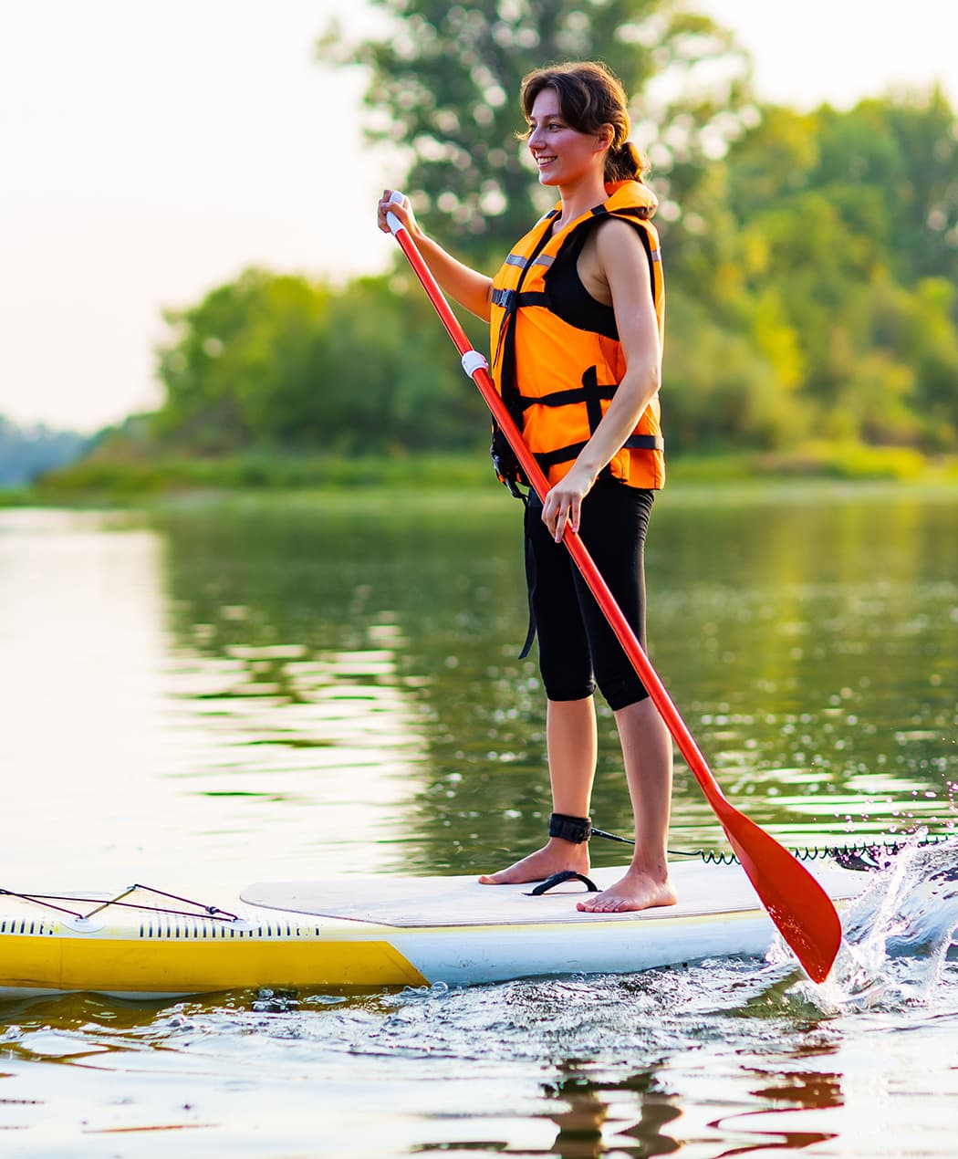 woman smiles paddling board on lake